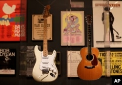 Guitars used by Jimi Hendrix, left, and Eric Clapton are displayed with concert posters at the exhibit "Play It Loud: Instruments of Rock & Roll," at the Metropolitan Museum of Art in New York, April 1, 2019.