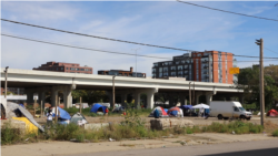 A tent encampment stands in contrast to sleek brick residential buildings in the North Loop neighborhood of Minneapolis, Minn. State rep. Esther Agbaje’s legislative interests include increasing affordable housing. (Betty Ayoub/VOA)