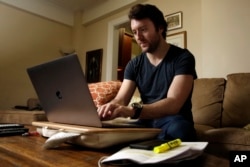 FILE - Journalist Michael Weiss works on his laptop in his apartment on New York's Upper West Side, Dec. 8, 2017.