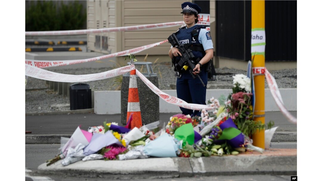 Police stand by a collection of flowers near the Linwood mosque in Christchurch, New Zealand, March 16, 2019, where one of the two mass shootings occurred.