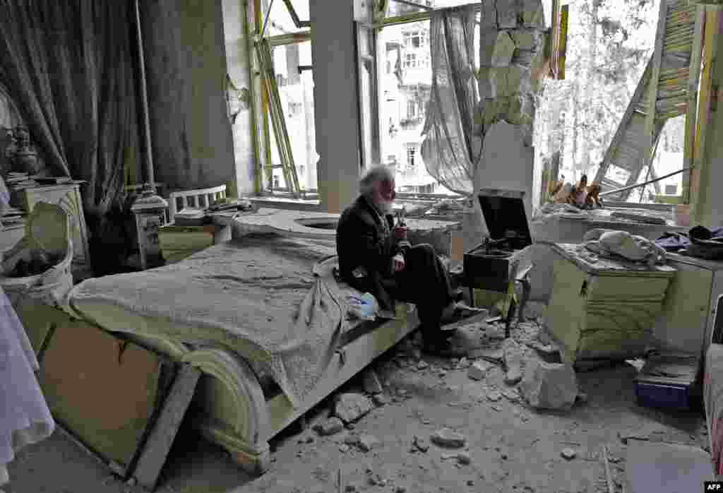 Mohammed Mohiedin Anis, or Abu Omar, 70, smokes his pipe as he sits in his destroyed bedroom listening to music on his vinyl player in Aleppo&#39;s formerly rebel-held al-Shaar neighborhood.