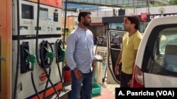 Rajesh Kumar, left, shares a ride to work with another employee, Dilip Swain, right, as higher petrol prices in India begin to be felt in people's pocketbooks.