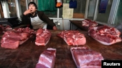 山西省长治市一名小贩在猪肉摊前等待顾客。