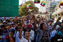 Warga mengibarkan bendera nasional dan militer ketika berpawai menunjukkan dukungan terhadap militer Myanmar di Yangon, 14 Oktober 2018.