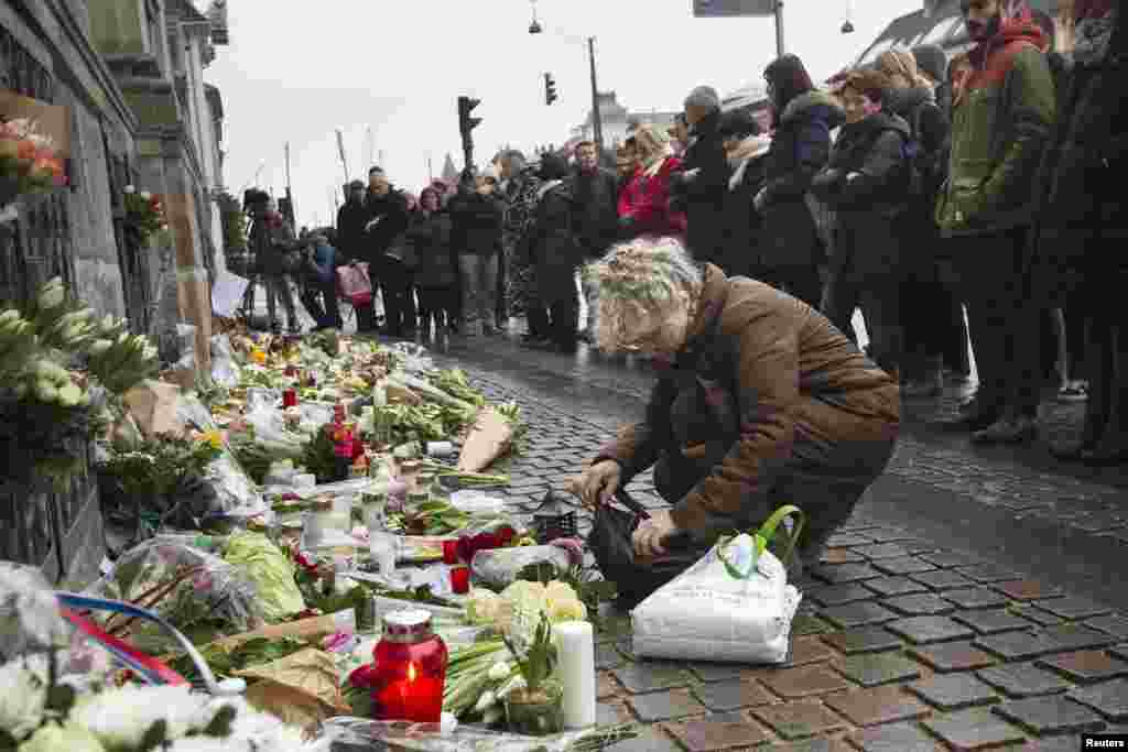 People place flowers during a minute of silence in front of the French Embassy in Copenhagen, Denmark, Jan. 8, 2015.