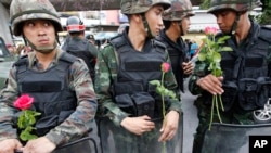 Soldiers hold roses given by supporters at Victory Monument, Bangkok, May 27, 2014.