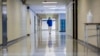 FILE - A middle school principal walks the empty halls of his school as he speaks with one of his teachers about her COVID-19 symptoms, in Wrightsville, Ga., Aug., 20, 2021. On Dec. 27, 2021, U.S. health officials cut isolation restrictions for Americans 