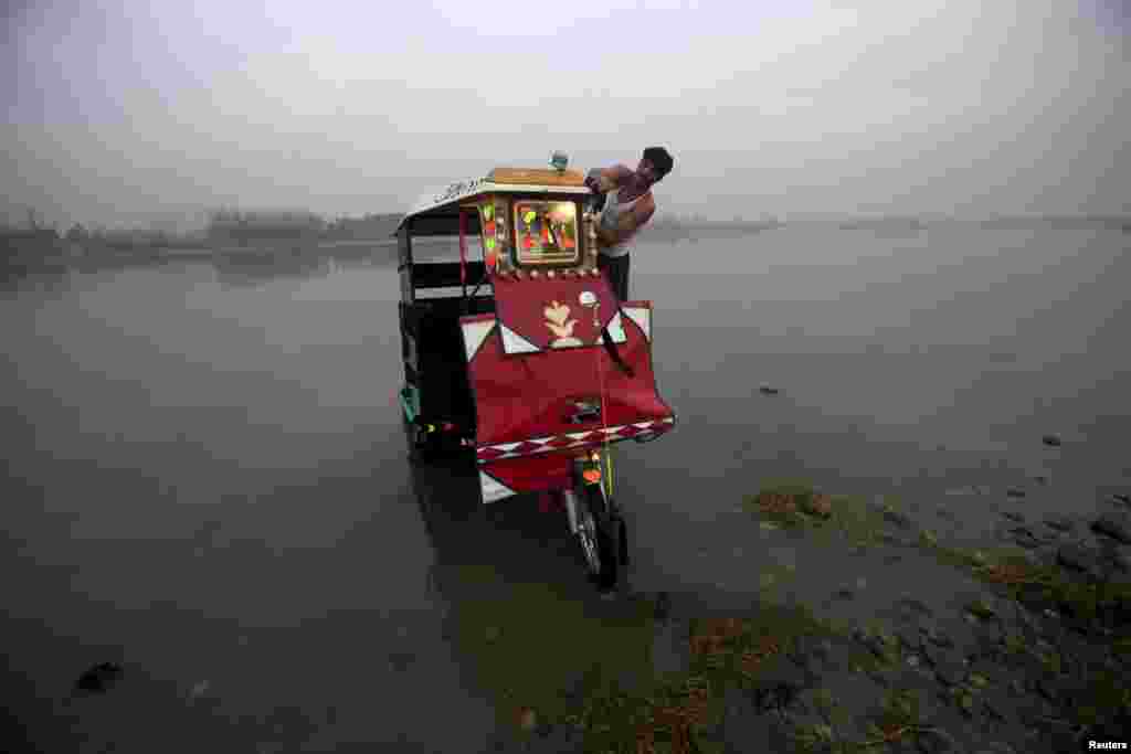 A man washes his rickshaw on the shores of the Sardaryab River in Charsadda near Peshawar, Pakistan.