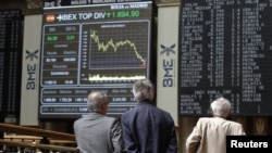 Traders look at electronic boards at the stock exchange in Madrid, June 11, 2012. 