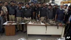 Police officers display confiscated ammunition and the dead bodies of terrorists who attacked the Jinnah International Airport Monday in Karachi, June 9, 2014. 