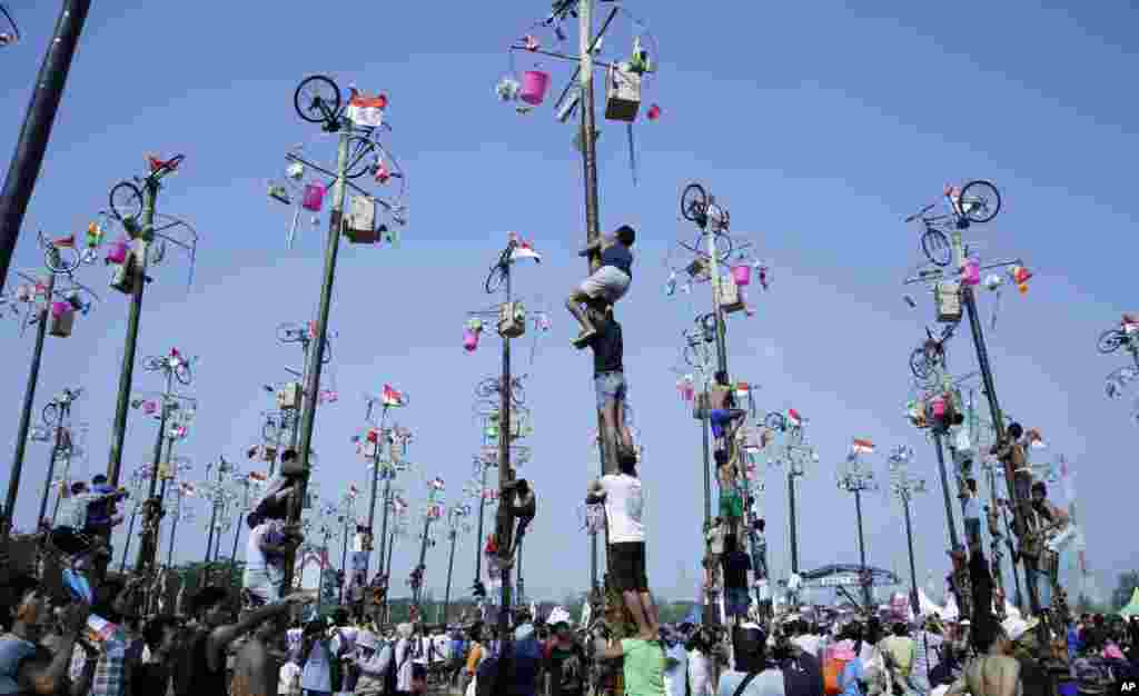 Indonesian men climb greased poles to retrieve prizes such as bicycles and rice cookers as part of the Independence Day festivities at Ancol Beach in Jakarta.
