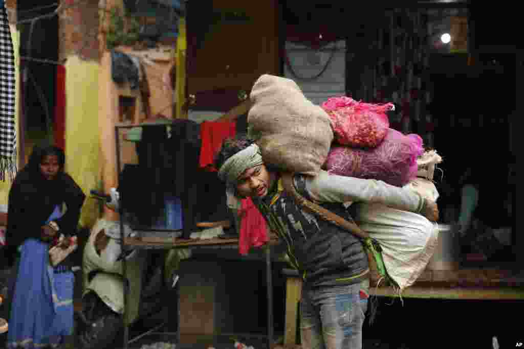 A worker carries vegetables on his back at a market in Lucknow, India.