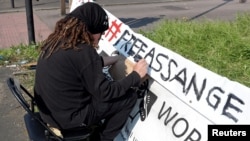 A protester writes his sign outside HMP Belmarsh prison where WikiLeaks founder Julian Assange is held, in London, Britain, April 15, 2019.