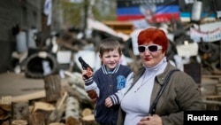 Un niño y su madre posan para una foto frente a una barricada en Slaviansk, al este de Ucrania.
