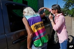 A clinic escort, left, speaks to a driver and patient while an abortion protester attempts to hand over some reading material outside the Jackson Women's Health Organization clinic in Jackson, Miss., April 10, 2019.