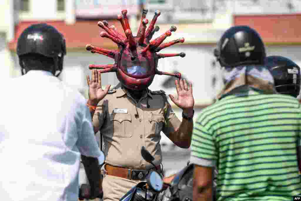 Police inspector Rajesh Babu wearing a coronavirus-themed helmet, speaks to motorists at a checkpoint during a government-imposed nationwide lockdown in Chennai, India, March 28, 2020.