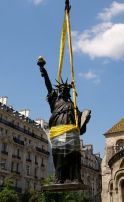 Replika asli Patung Liberty setinggi 2,83 meter diangkat oleh derek dari luar Musee des Arts et Metiers di Paris sebelum berangkat ke Pulau Ellis di New York. (Foto: REUTERS/Noemie Olive)