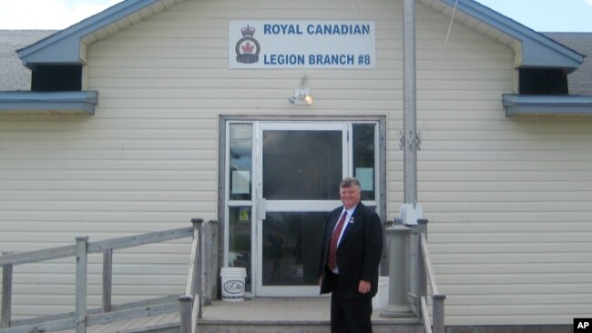 FILE - Gander, Newfoundland, Canada Mayor Claude Elliott stands in front of the Royal Canadian Legion Hall. At this remote town with a population of about 10,000 and an international airport built before World War II, 38 planes carried in 6,600 passengers
