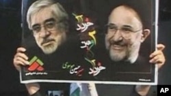 A protester holds up a poster of Iranian opposition leader Mir Hossein Mousavi (L) and reformist former president Mohammad Khatami during an anti-government rally in Tehran, 27 Dec 2009