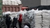 FILE - North Koreans distribute imported sacks of flour on the banks of Yalu River, near the North Korean town of Sinuiju, opposite the Chinese border city of Dandong, Jan. 27, 2014. 