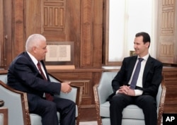 In this photo released by the Syrian official news agency SANA, Syrian President Bashar Assad, right, meets with Iraq's National Security Adviser Faleh al-Fayadth, in Damascus, Syria, May. 18, 2017.