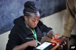 An offical from the electoral commmision registers voters through a fingerprint scan machine at the Panarae Primary School in Kajiado, Kenya, Aug. 8, 2017.