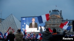 President-elect Emmanuel Macron is seen on a giant screen near the Louvre museum.