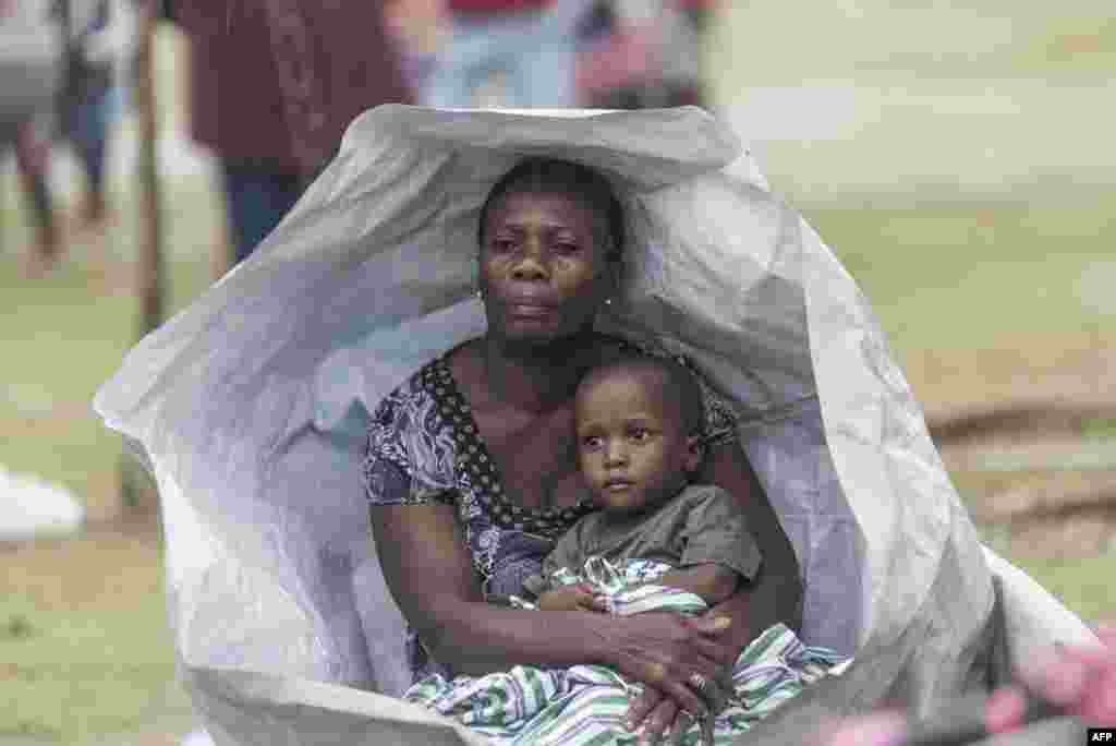 People shelter from rain under a tarp as Tropical Storm Grace approaches Les Cayes, Haiti.