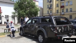 Children stand next to a vehicle belonging to the Committee Against Torture which was damaged, near its headquarters in Grozny, Russia, June 3, 2015. 