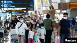 Orang-orang berjalan dengan membawa barang bawaannya di Bandara Soekarno-Hatta untuk kembali ke kampung halaman mereka, di tengah wabah COVID-19 di Tangerang, di pinggiran Jakarta, 4 Mei 2021. (Foto: REUTERS/ Ajeng Dinar Ulfiana)