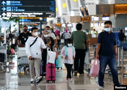 Orang-orang berjalan dengan barang bawaan mereka di Bandara Soekarno-Hatta untuk kembali ke kampung halaman atau "mudik." (Foto: Reuters)