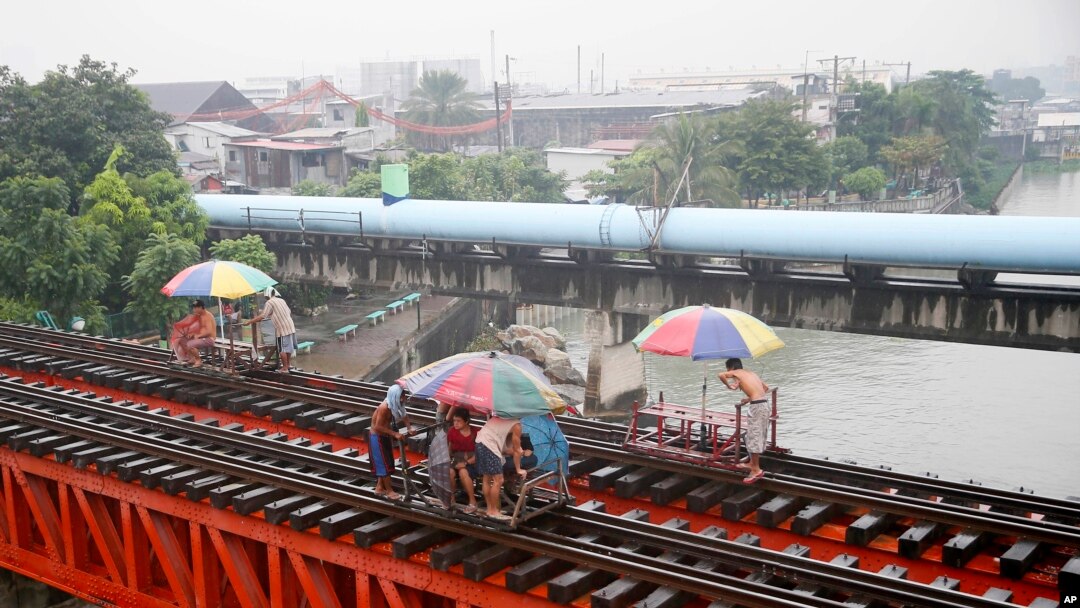 Warga naik "trolley", kereta yang dibuat oleh penduduk setempat sebagai alat transportasi dengan memanfaatkan jalur kereta api saat topan yang memicu hujan mulai mengguyur kota Manila, Filipina (17/10). 