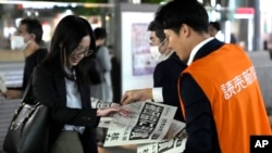 A worker of the Yomiuri Shimbun newspaper hands out copies of an extra version to passersby in Tokyo, Oct. 11, 2024, after Nihon Hidankyo won the Nobel Peace Prize.