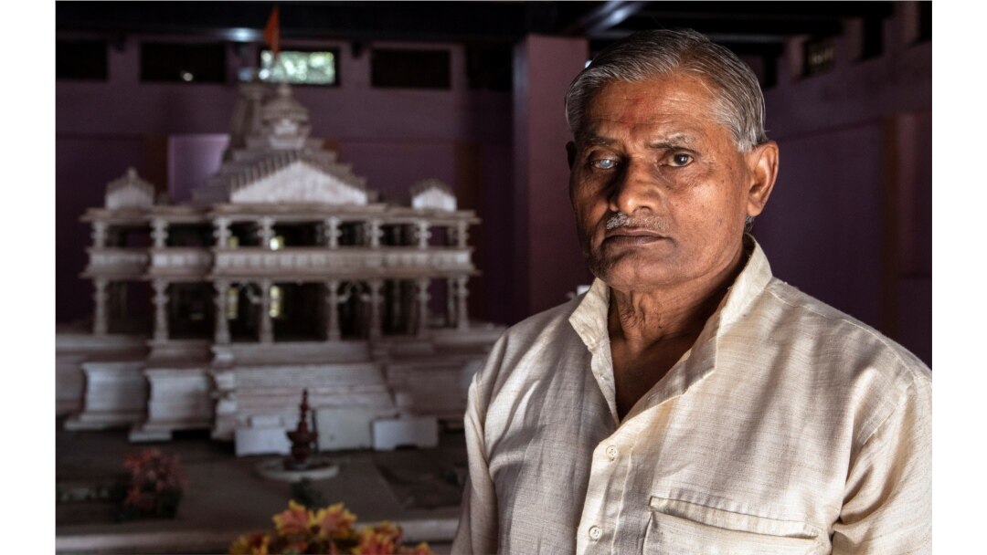 Hajari Lal, a devotee who participated and was injured during the demolition of Babri mosque, poses in front of the model of proposed Ram temple that Hindu groups want to build at a religious site in Ayodhya, India, Oct. 22, 2019.