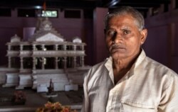 Hajari Lal, a devotee who participated and was injured during the demolition of Babri mosque, poses in front of the model of proposed Ram temple that Hindu groups want to build at a religious site in Ayodhya, India, Oct. 22, 2019.