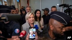 French far-right leader Marine Le Pen is flanked by police officers as she arrives at the court house in Paris, Sept. 30, 2024. 