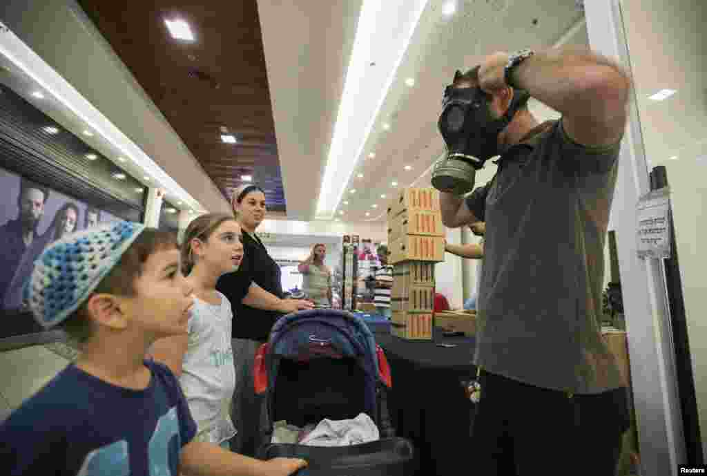 An Israeli man shows his children how to adjust a gas mask at a distribution point at a shopping mall in the West Bank Jewish settlement of Maale Adumim, near Jerusalem.