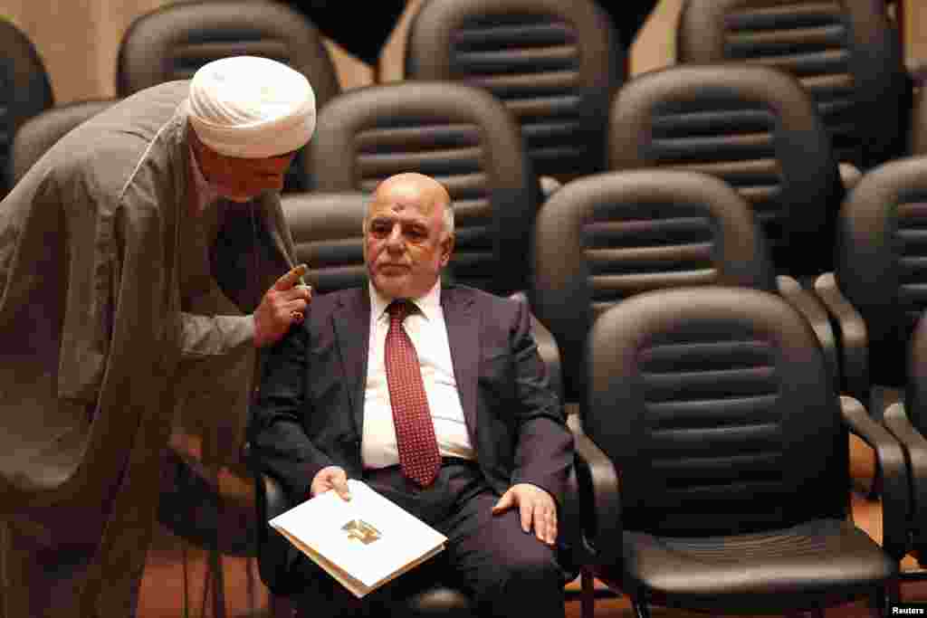 Shiite Sheikh Humam Hamoudi (left), Iraq&#39;s new deputy speaker of the Iraqi Council of Representatives, speaks with Iraq&#39;s incoming Prime Minister Haider al-Abadi as they attend a parliamentary session to vote on Iraq&#39;s new government at the parliament headquarters, Baghdad, Sept. 8, 2014.