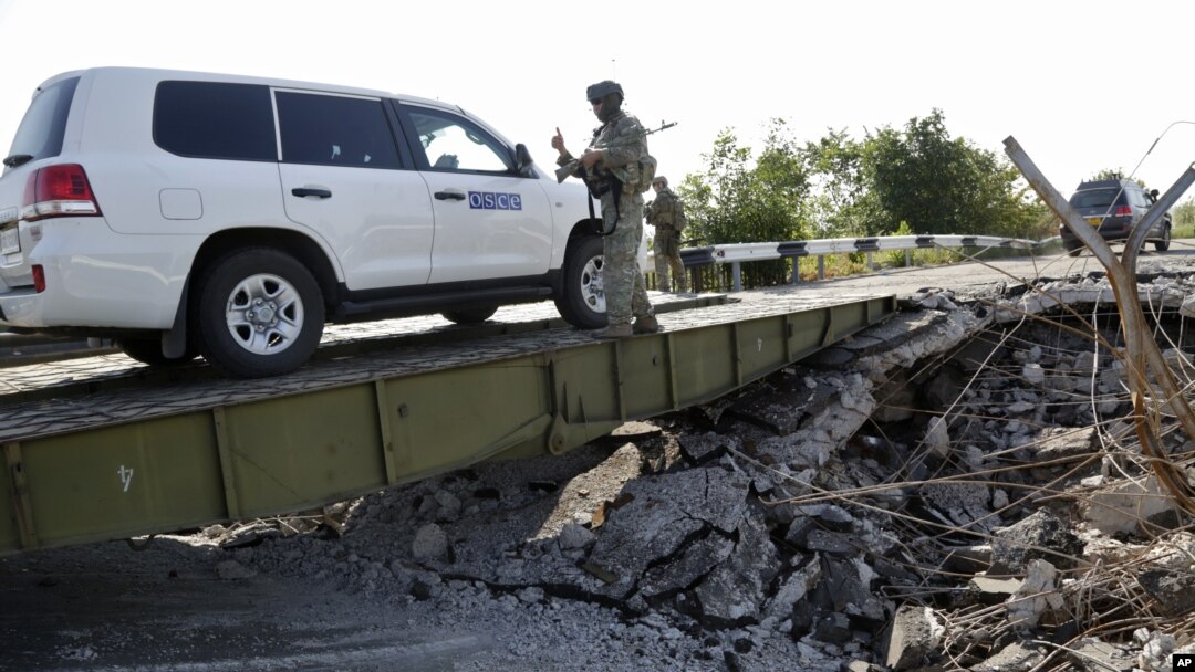 Mobil yang mengangkut tim forensik dan anggota OSCE dalam misi mereka di Ukraina melewati sebuah jembatan yang rusak di Debaltsevo, Ukraina timur (3/8/2014). 