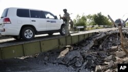 Mobil yang mengangkut tim forensik dan anggota OSCE dalam misi mereka di Ukraina melewati sebuah jembatan yang rusak di Debaltsevo, Ukraina timur (3/8/2014). 