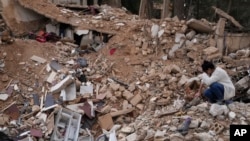 Lina Rida Jawhari menangis saat duduk di reruntuhan rumah keluarganya yang hancur di Baalbek, Lebanon timur, Kamis, 28 November 2024. (/Hassan Ammar/AP)