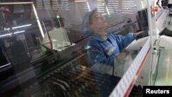 An employee working on the production line of an electronics factory is seen reflected on an equipment, in Jiaxing, Zhejiang province, China, April 2, 2019. 