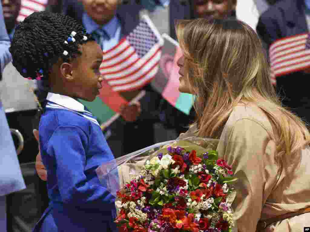 Melania Trump recebida por uma menina com flores à chegada no aeroporto Internacional de Lilongwe em Lumbadzi, Malawi. 4 de Outubro, 2018.