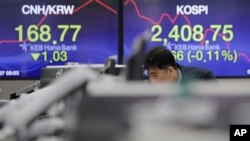 A man watches computer monitors near the screens showing the Korea Composite Stock Price Index (KOSPI), right, and the foreign exchange rate at the foreign exchange dealing room in Seoul, South Korea, March 7, 2018.