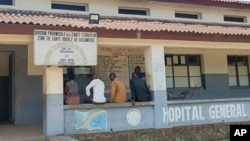 Men sit outside the general hospital in Basankusu, Democratic Republic of Congo, where some victims of unidentified illnesses are being treated, Feb. 27, 2025.