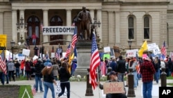 Protesters rally at the State Capitol in Lansing, Mich, April 30, 2020. Gun-carrying protesters have been a common sight at some demonstrations calling for coronavirus-related restrictions to be lifted. 