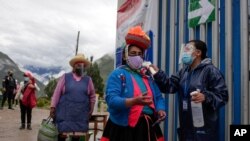 Un funcionario electoral toma la temperatura a una mujer a la entrada de un sitio de votación en Ollaytambo, Perú, en el día de elecciones generales el 11 de abril de 2021. 