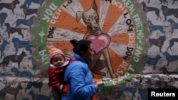 A Tibetan exile carries her child as she walks toward the Tsuglagkhang temple in Dharamsala, India, March 19, 2016.