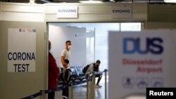 FILE - Travelers line up at the new Corona Test Center at Duesseldorf Airport in Duesseldorf, Germany, July 27, 2020. Travellers can take a voluntary test for the coronavirus disease following travel to avoid two weeks of quarantine.