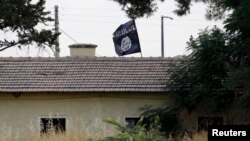 FILE - An Islamic State flag flies over the customs office of Syria's Jarablus border gate as seen from the Turkish town of Karkamis, in Gaziantep province, Turkey, Aug. 1, 2015.